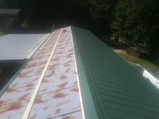 Old rusted panels beside newly installed green metal roofing — Wind Damage Roof Repair by Roofing Brothers in Schaefferstown