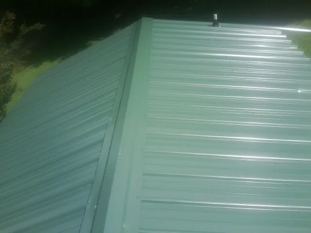 New green metal panels meeting at the ridge of a roof — Flat Roof Repair work by our crew in Schaefferstown