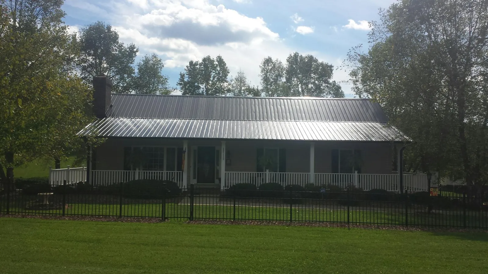 Gray metal roof on a brick ranch with a full width front porch — Gutter Guard Installation work by our crew in Schaefferstown