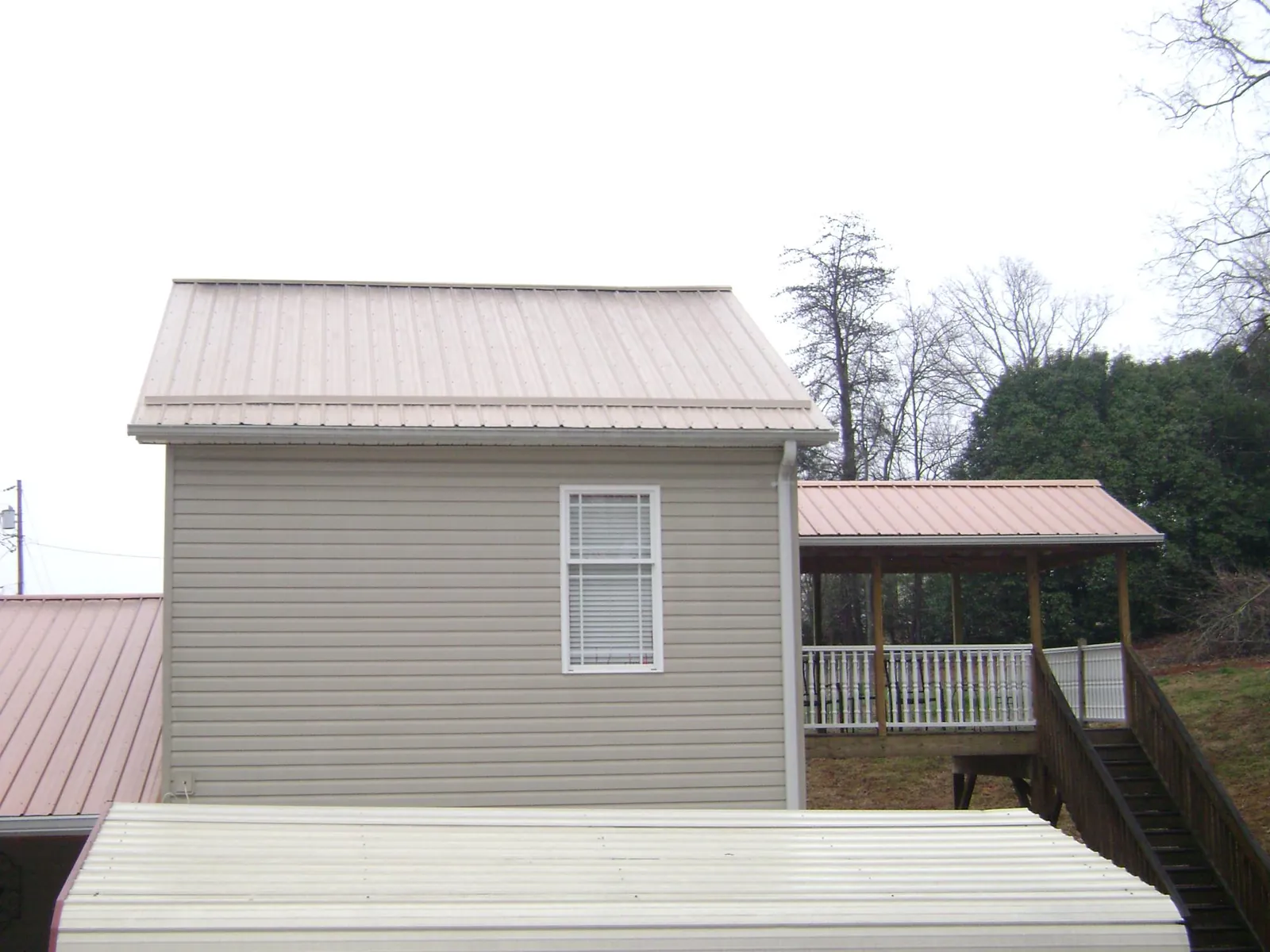 Tan metal roofs on a two story addition and attached porch, from a Roof Replacement job in Schaefferstown