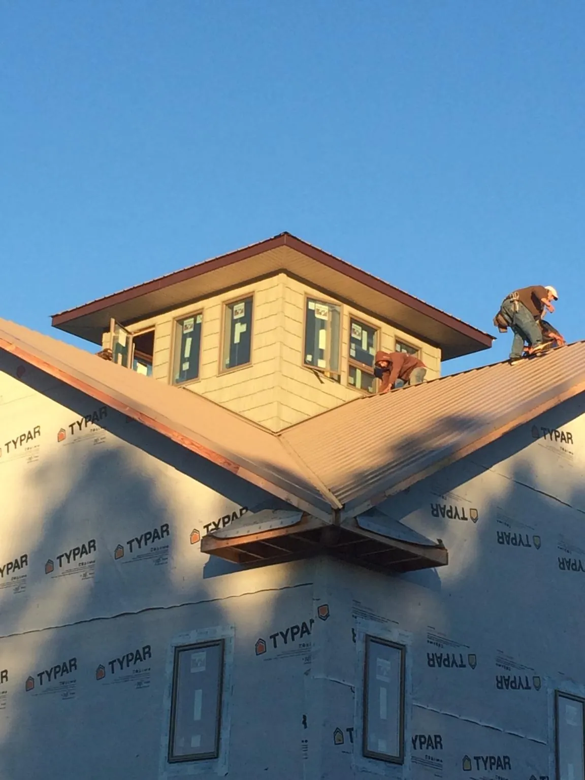Roofers working around a rooftop cupola on a new metal roof at sunset — Roof Waterproofing in Schaefferstown by Roofing Brothers